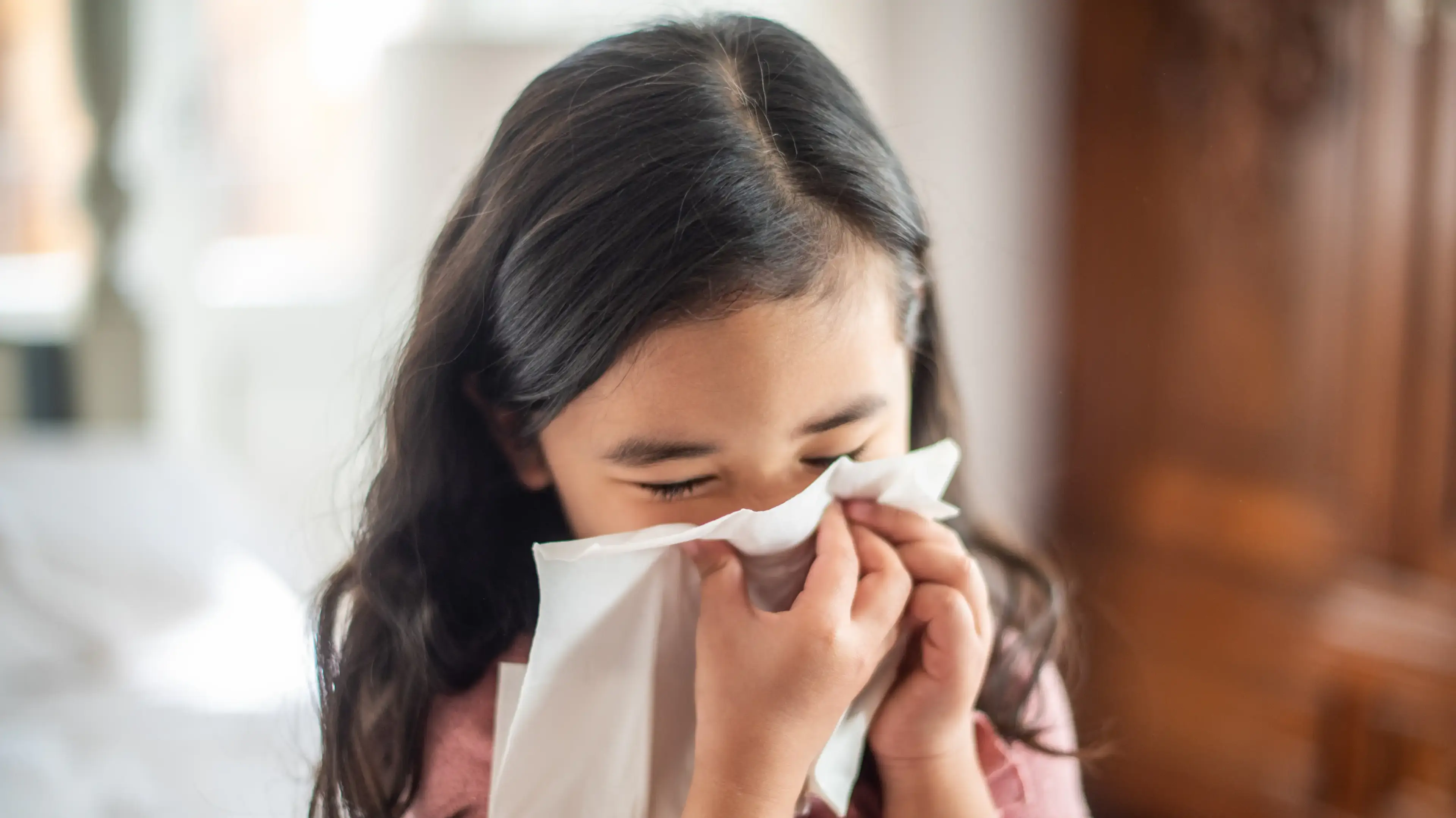 Child blowing her nose due to allergy symptoms