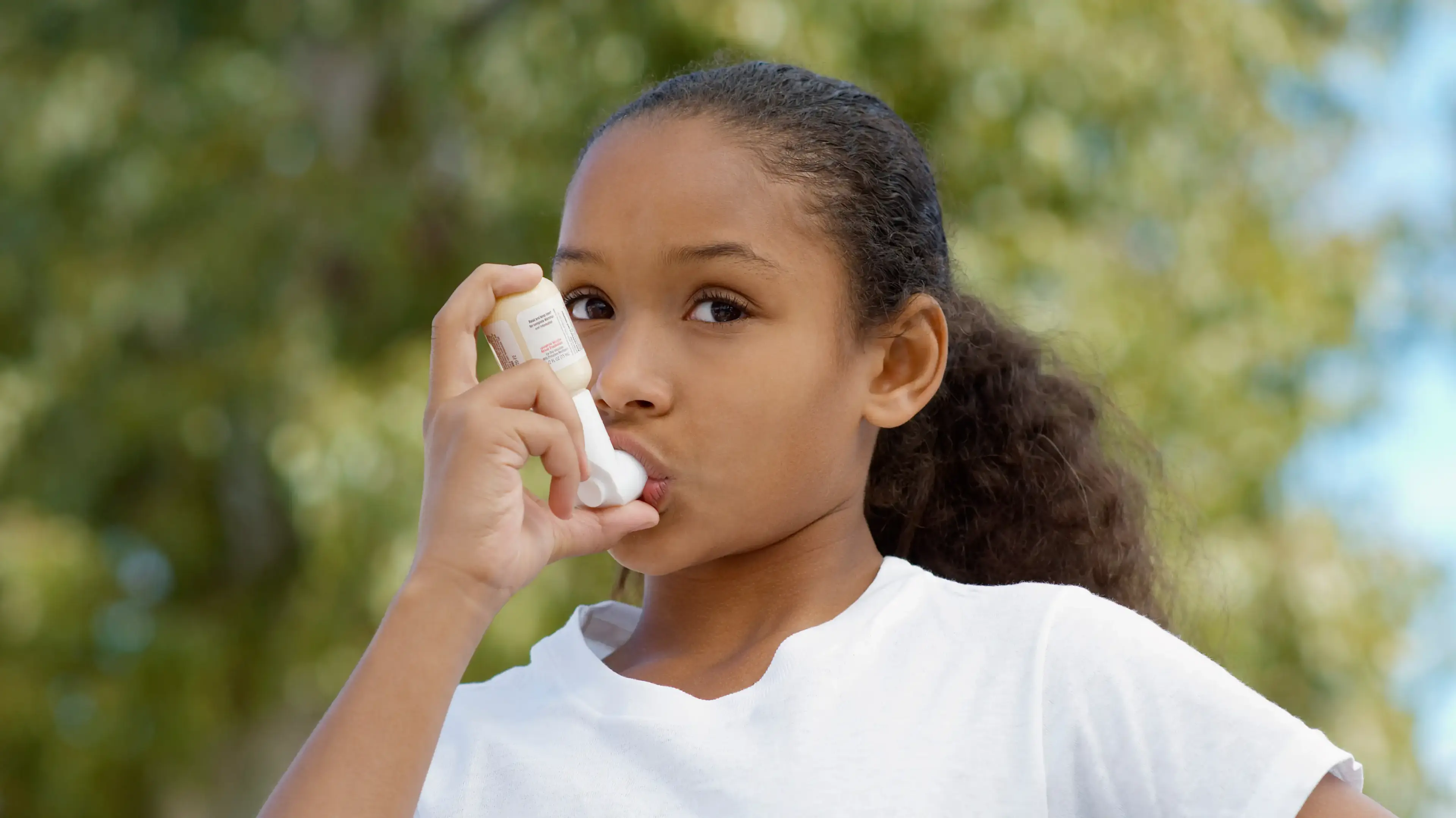 Child using an inhaler outdoors to manage asthma