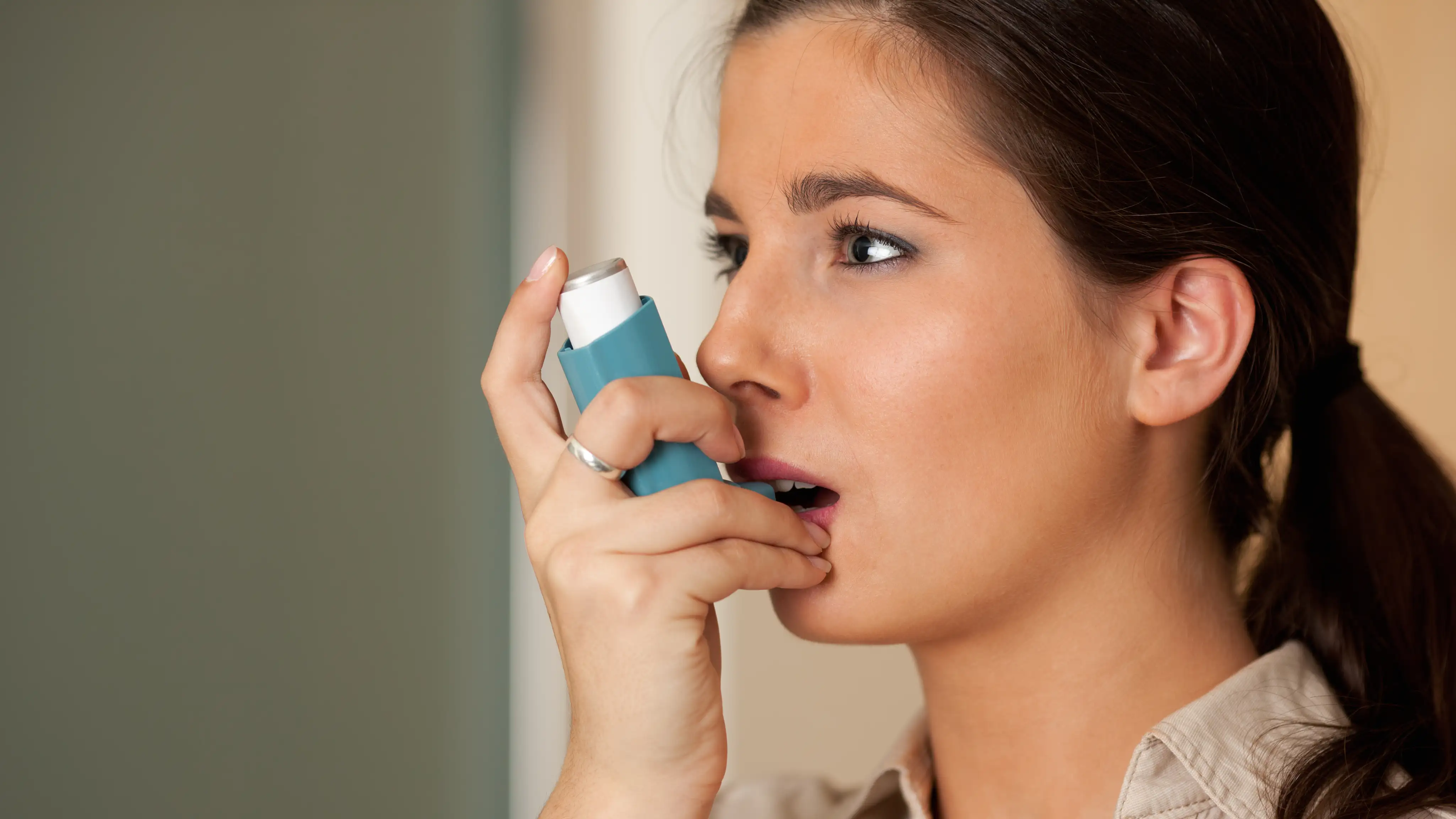Adult using an inhaler to manage asthma